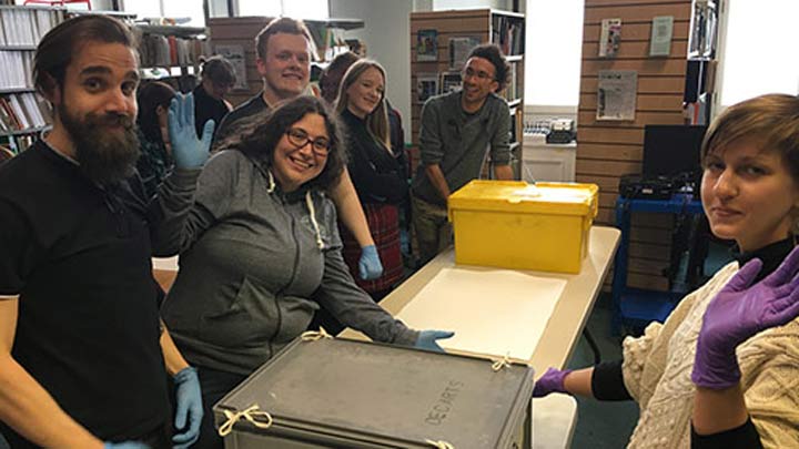 students with art-handling gloves and boxes