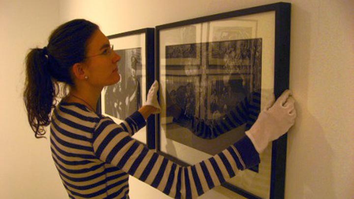 Female hanging picture in gallery setting