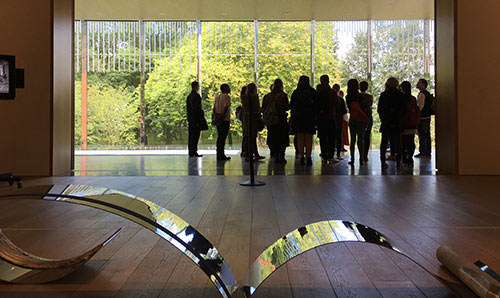 A group of students looking out of a window in an exhibition space at the Whitworth Art Gallery