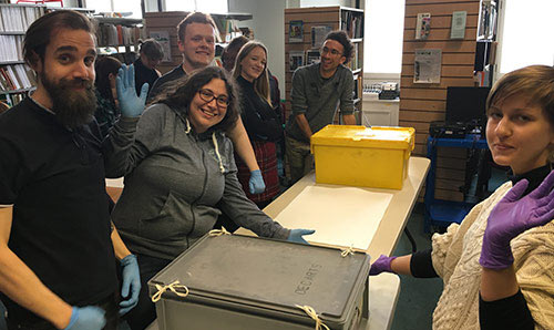 Students in an exhibition space smiling to camera